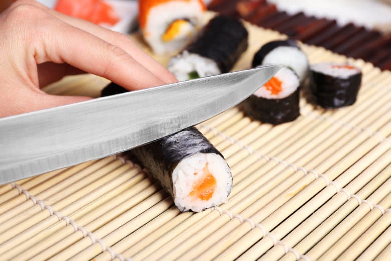 Closeup Of Knife Cutting Sushi